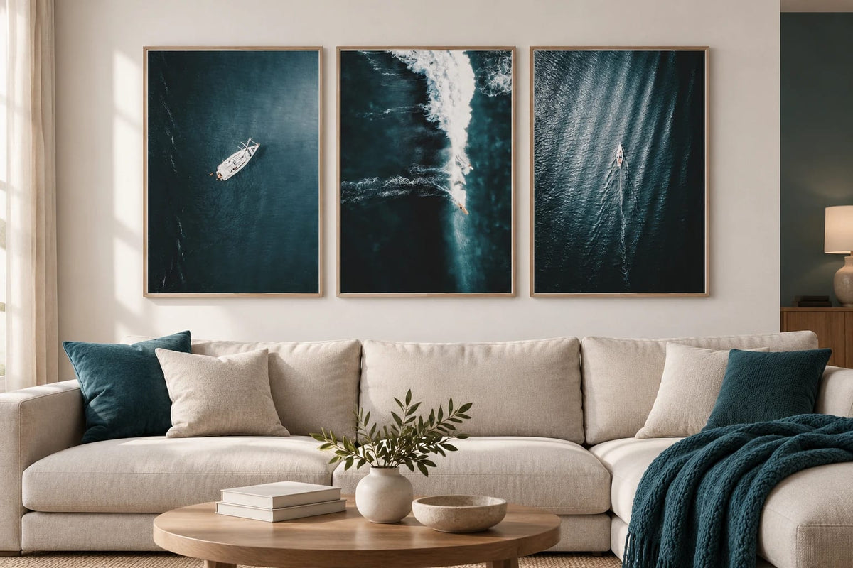 Dark sea prints above a light sofa with turquoise pillows.