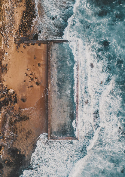rectangular coastal pool beside cliffs and surf.