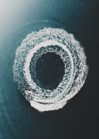 boat leaving a round white wake on dark sea.