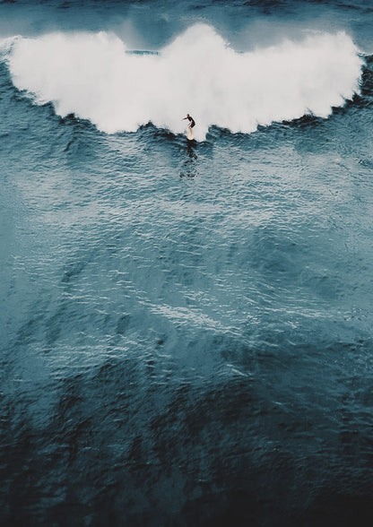 surfer before a breaking white wave.
