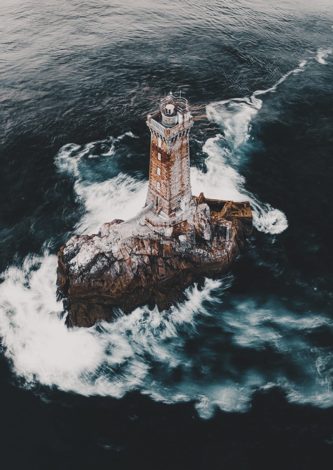 lighthouse on a rocky island amid foam.