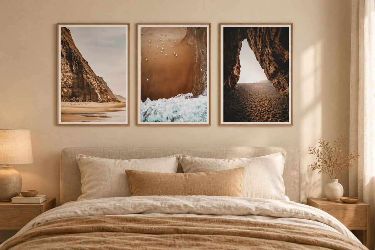 Three shore views above a bed in a beige bedroom.
