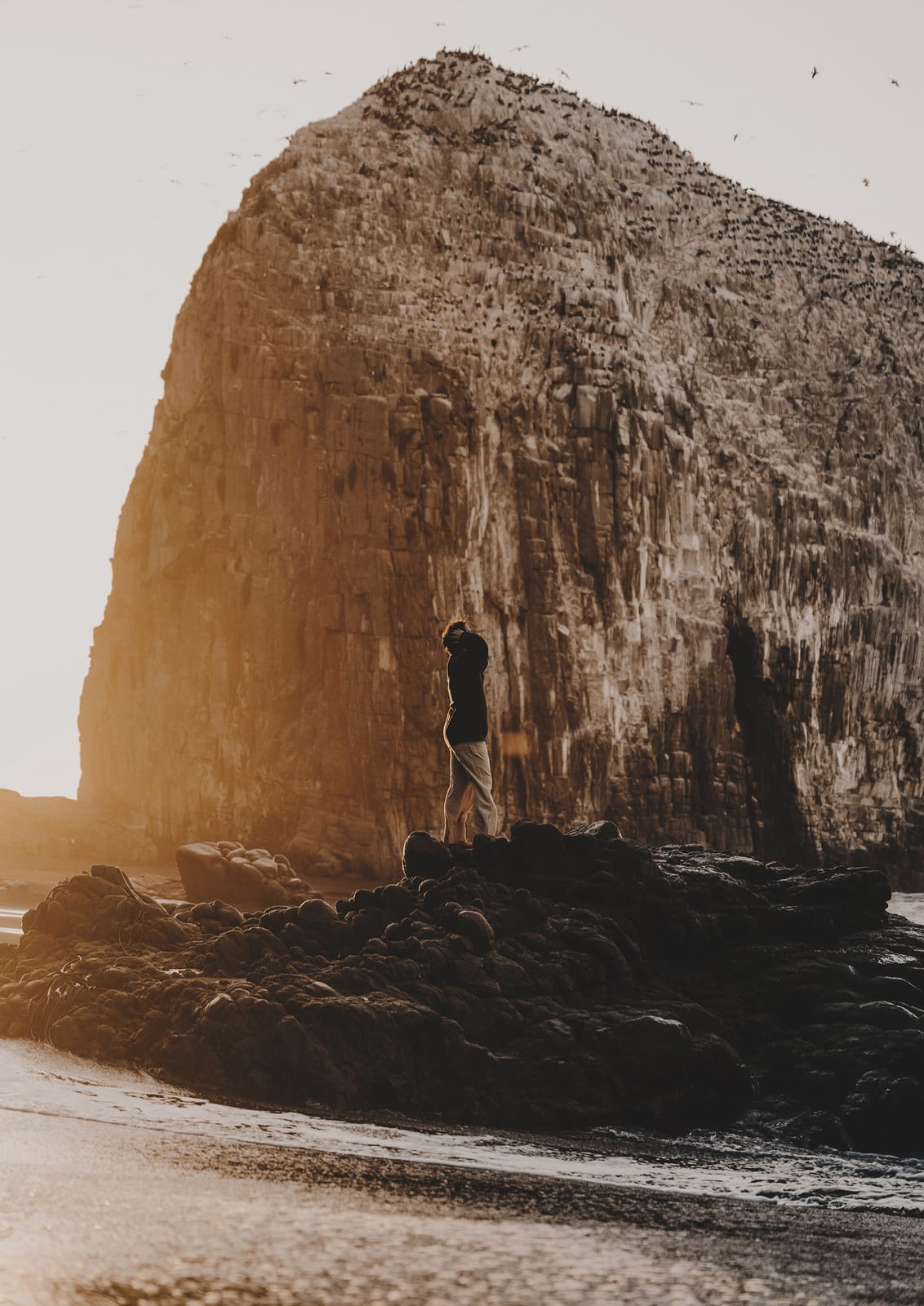 person before a rocky coastal wall.