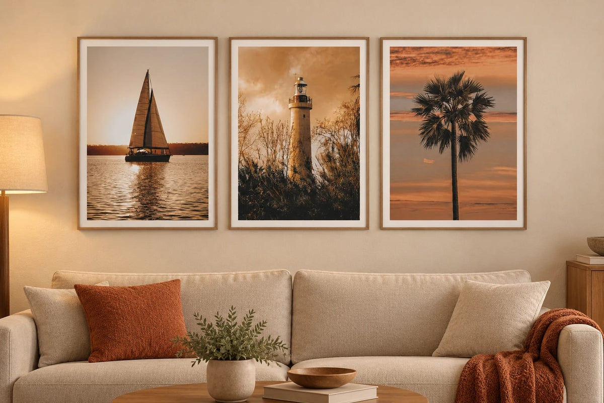 Three warm-toned prints above a sofa with terracotta cushions.