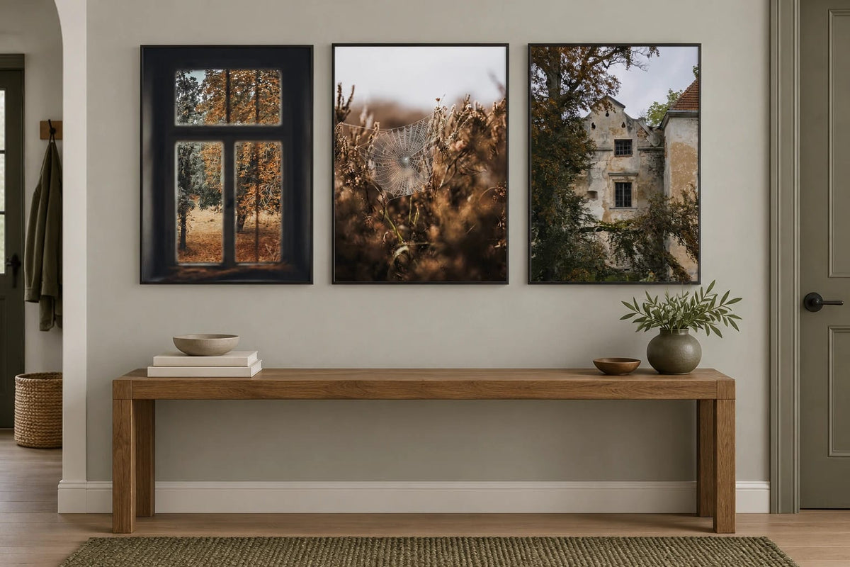 Three muted autumn prints above an oak console in a gray entryway.