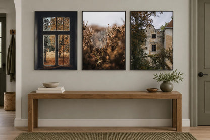 Three muted autumn prints above an oak console in a gray entryway.