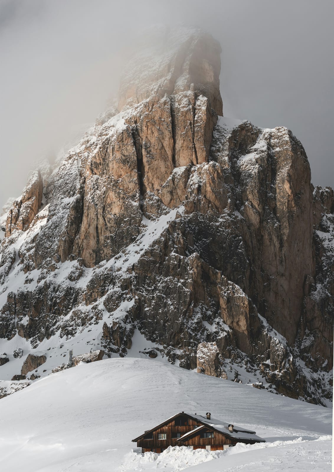 A wooden cabin sits on a snowy slope.