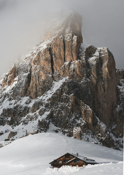 A wooden cabin sits on a snowy slope.