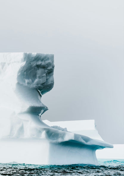 An iceberg rises above blue water.