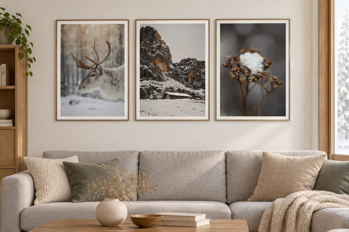 Three winter scenes hang above a light sofa.