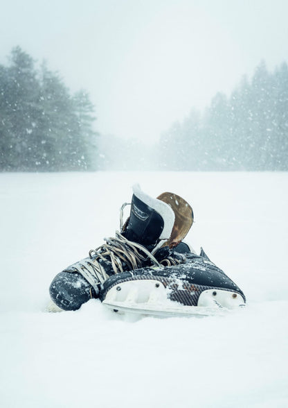 A pair of dark skates rests on snow.