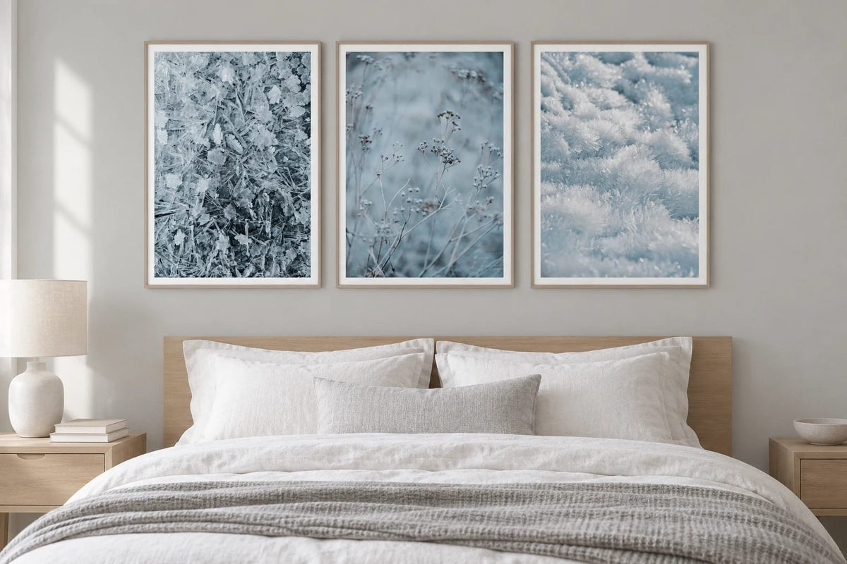 Three blue winter prints hang above a bed.