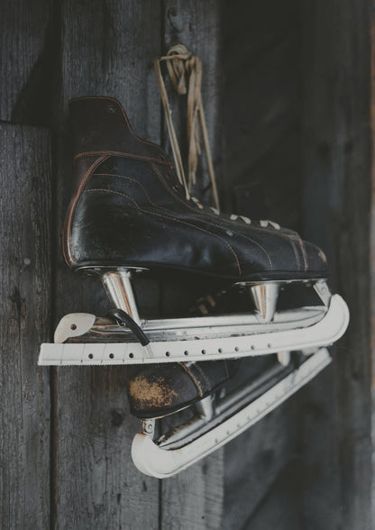 Dark skates rest against a wooden surface.