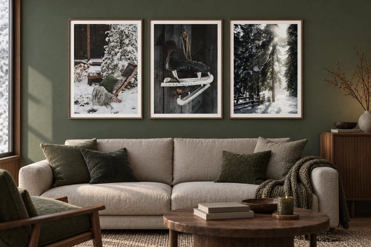 Three winter scenes hang above a light sofa on an olive wall.