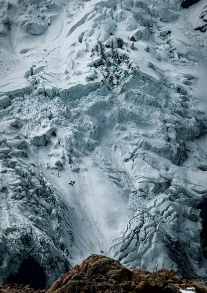 A blue-white icy cliff shows a brown stone edge.