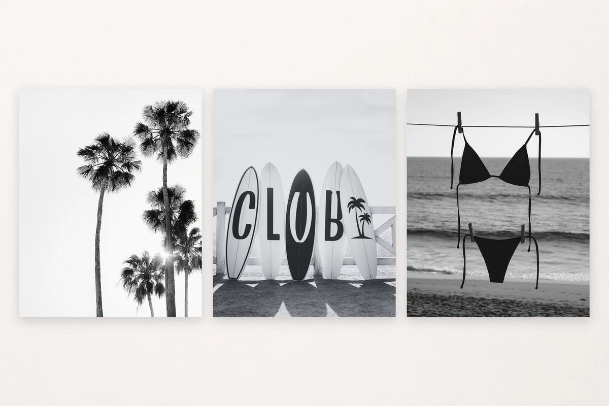 Three monochrome coastal prints show palm trees, surfboards, and a swimsuit near the shore.