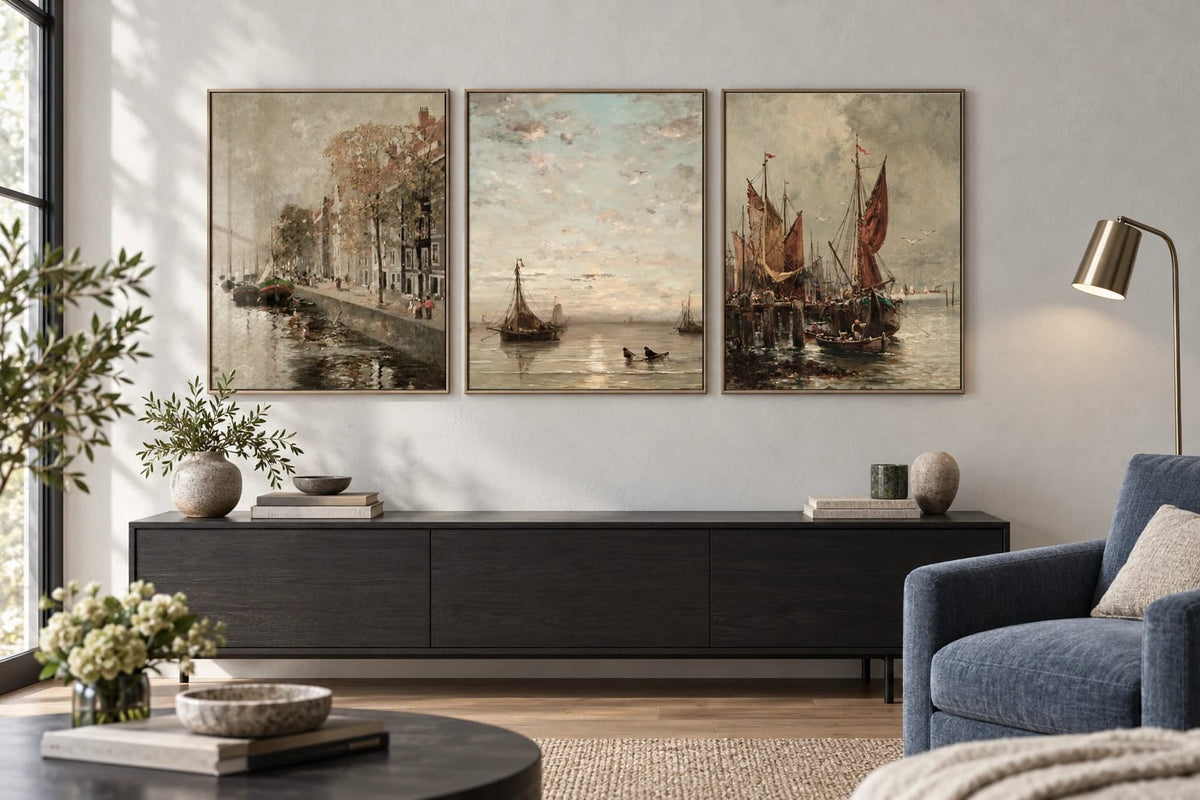 Harbor prints grouped above a dark cabinet beside a blue chair.