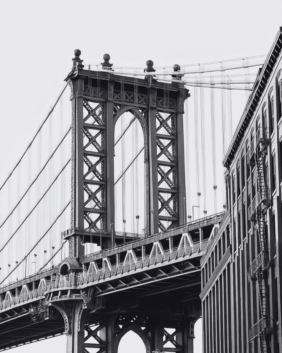 A suspension bridge in a black-and-white city photograph.