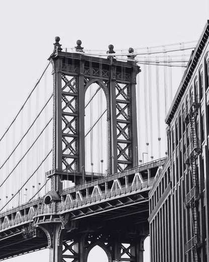 A suspension bridge in a black-and-white city photograph.