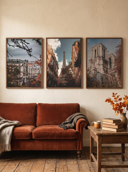 Three city prints above a rust-colored sofa.