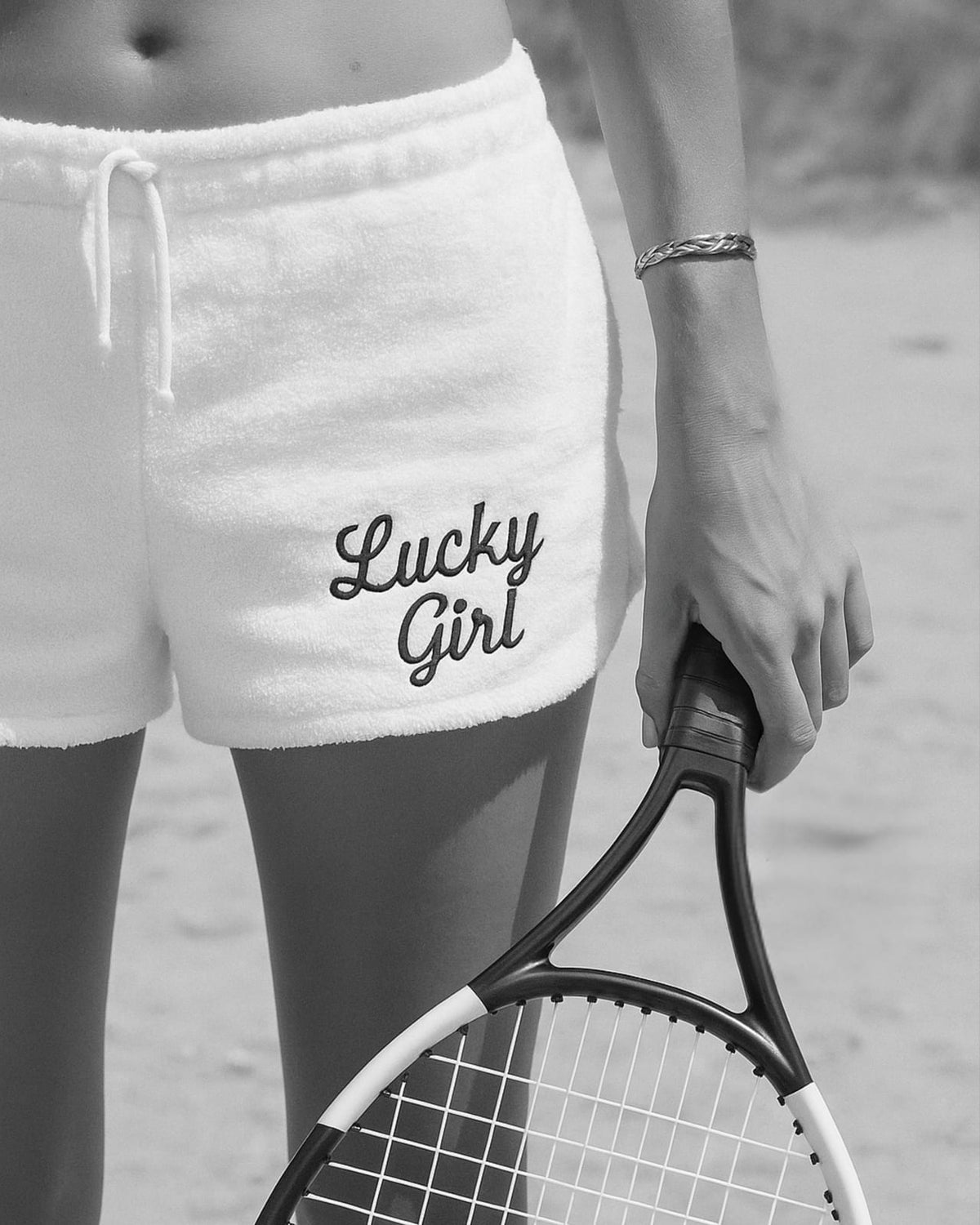 Shorts marked Lucky Girl beside a tennis racket.