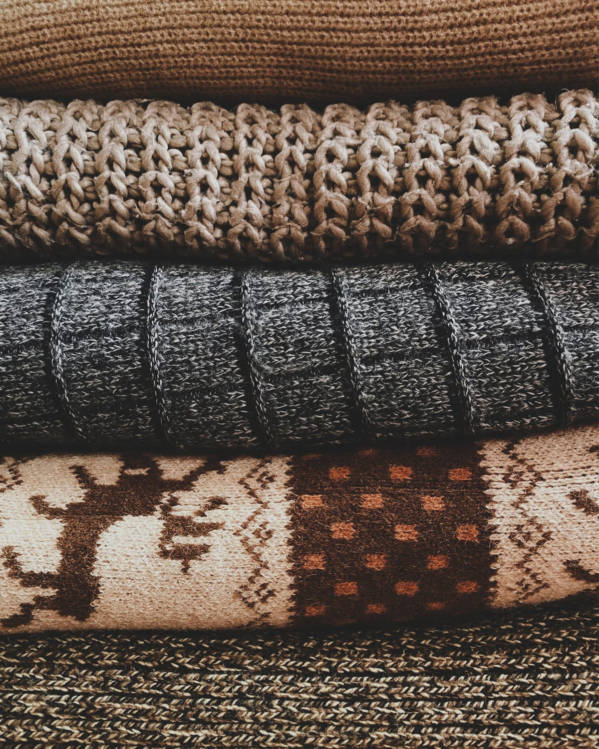 Folded knitted blankets with patterned textures.