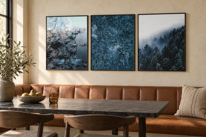 Frost and forest prints arranged above a dining table.