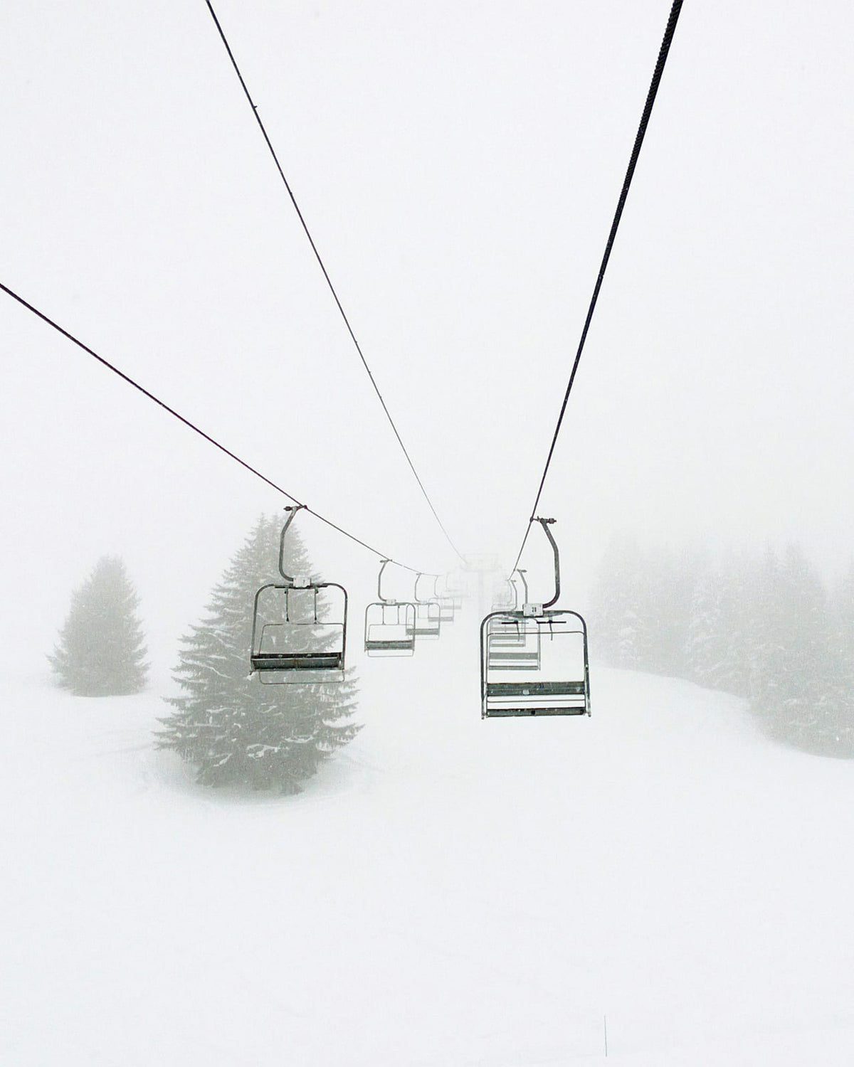 Chairlift seats above a snowy slope.