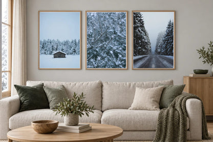 Three winter prints hang above a light sofa with green pillows.