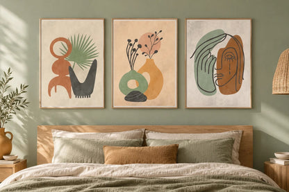 Three botanical prints hang above a bed against a green wall.