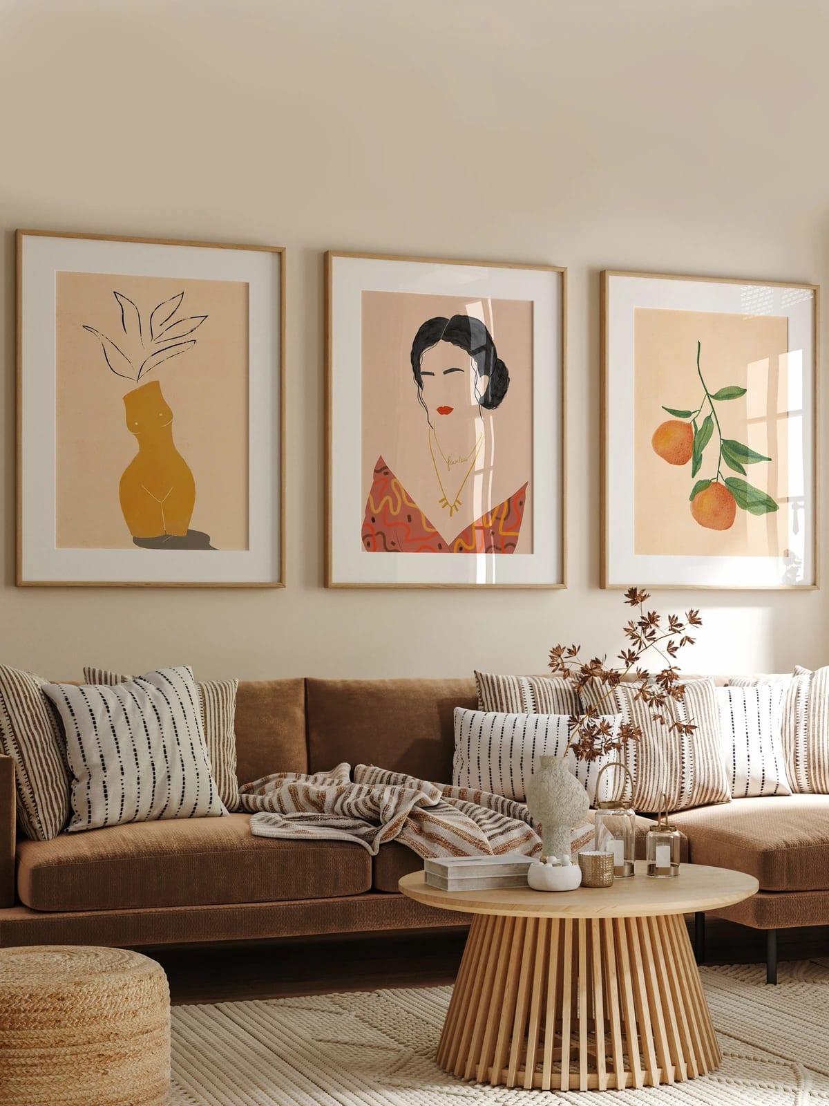 Three prints hang above a brown sofa on a beige wall.
