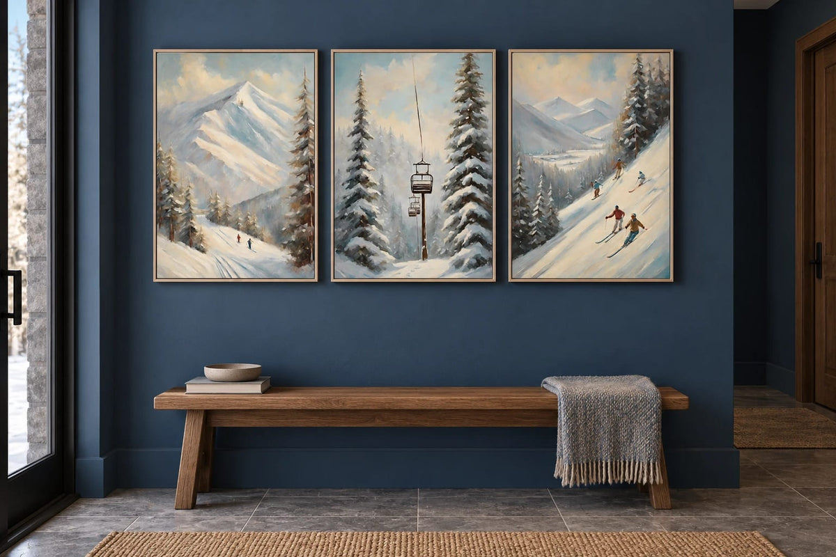 Three snowy mountain prints hang on a blue wall above a long wood bench.