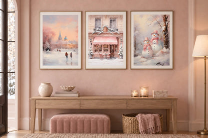 Three winter prints hang above a console in a pale pink entryway.