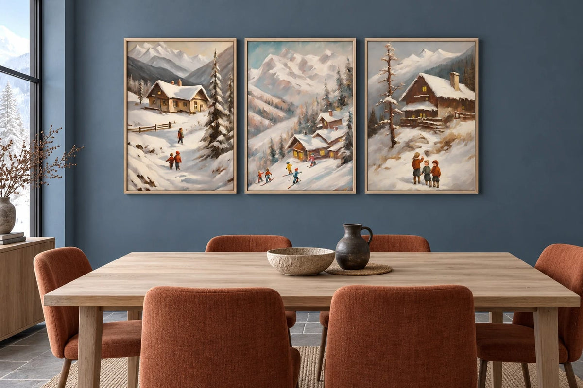 Three winter prints hang above a light dining table on a blue-gray wall.
