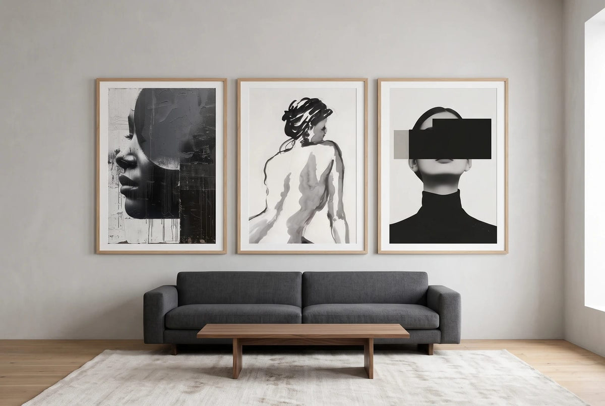 Monochrome portraits displayed above a graphite sofa in a light room.