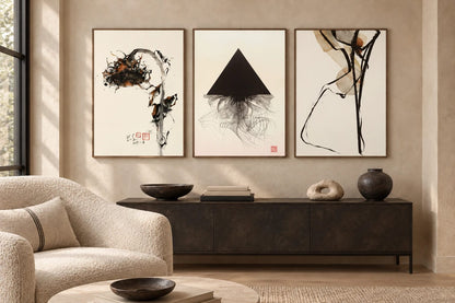 Three abstract prints hang above a dark console on a light living-room wall.