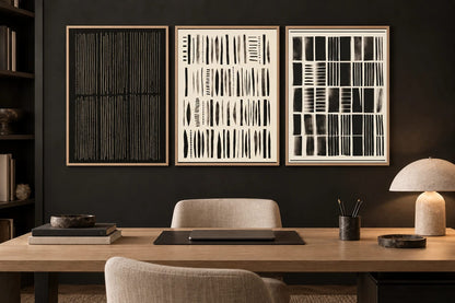 Three geometric prints hang above a desk on a dark wall.