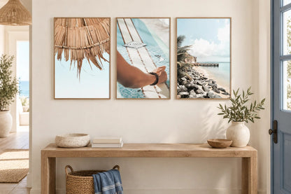 Three coastal prints above an oak console by a window.