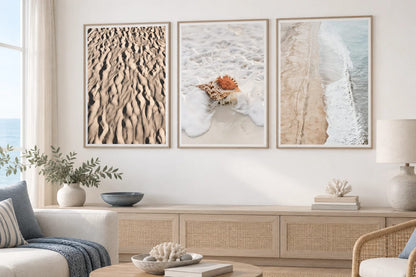 Three sand and shoreline prints in a bright room with woven furniture.